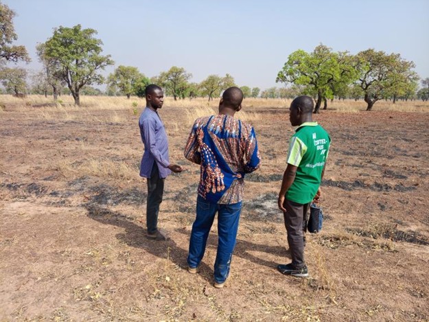 Three men discussing on a field which shows burned spots